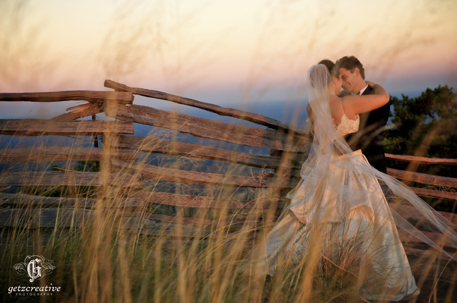 bride & groom by fence at sunset cliffs at glassy - wedding photography